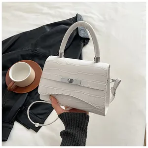 Close-up of white embossed croc-texture handbag with silver rotating metal lock detail