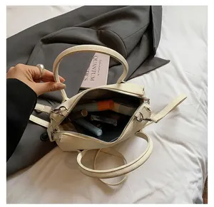 Detail of compact off-white leather bag interior showing space for cosmetics and silver hardware