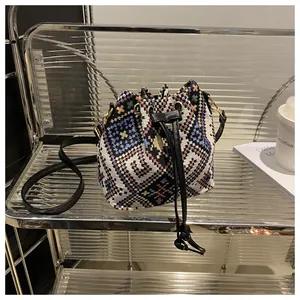 Detail of ethnic jacquard woven bucket bag with drawstring closure and golden hardware