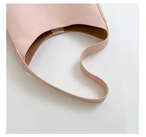 Detail view of pink leather handbag showing comfort shoulder strap and brown inner lining