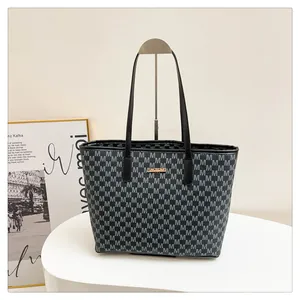 Close-up of golden metal logo plaque and M-letter pattern on black tote bag
