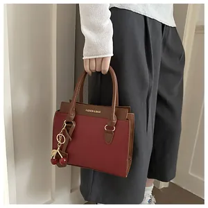 Détail du sac à main en cuir rouge avec breloque cerise et lettrage doré de mode
