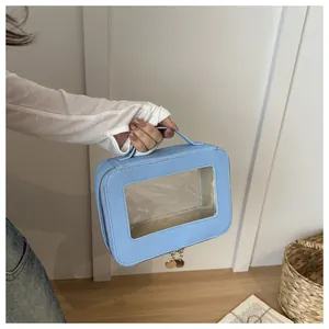 Close-up of hand holding a light blue waterproof cosmetic bag with a clear PVC window