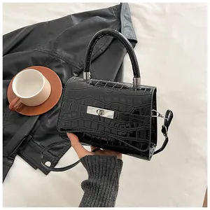 Detail of black crocodile embossed handbag with silver buckle and structured top handle