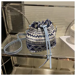Detail of ethnic style drawstring bucket bag with blue geometric canvas and leather strap