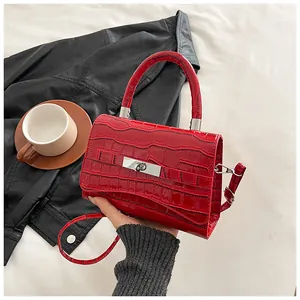 Detailed close-up of red crocodile pattern handbag with silver rectangular metal lock