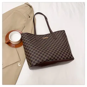 Top view of a brown tote bag with letter patterns next to a coffee cup and blazer