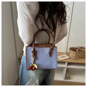 Vue détaillée du sac à main patchwork lavande et marron avec breloque cerise et texte doré
