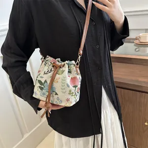 Ethnic embroidered bucket bag with floral patterns and leather straps on model