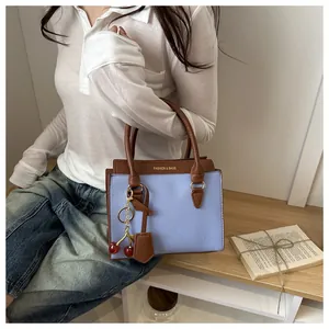 Détail d'un sac à main en cuir grainé violet et marron avec pendentif cerise