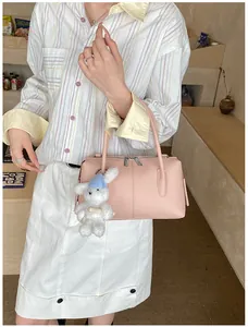 Detail of pink lychee leather handbag with double zippers and cute white rabbit charm