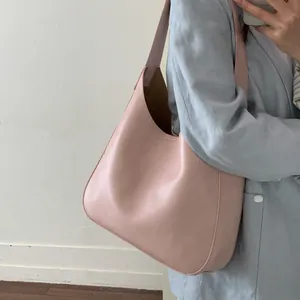 Pink leather hobo bucket bag with a wide shoulder strap shown on a female model