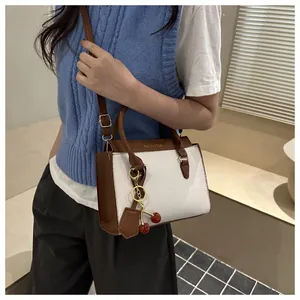 Détail d'un sac à main bicolore avec breloques cerise et bandoulière réglable