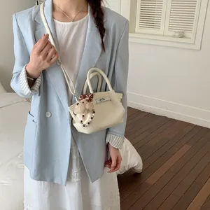 Dettaglio mini borsa a secchiello bianco panna con fibbia, ciondolo peluche e perline