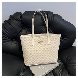 Detailed view of cream tote bag with monogram pattern and gold logo plaque
