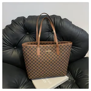 Detailed close-up of brown tote bag with M letter prints on a leather sofa