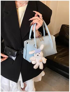 Detail of light blue lychee texture handbag with cute white rabbit charm on side