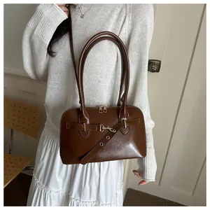 Detailansicht der braunen Leder-Muscheltasche mit Metallschnalle und Schultergurt am Model