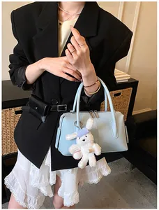Detail of light blue boston bag with lychee texture and white rabbit charm accessory