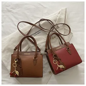 Détail de sacs à main en cuir grainé de qualité avec breloques cerise en marron et bordeaux