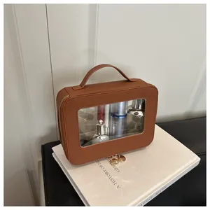 Detail view of caramel brown leather makeup bag with clear PVC window and dual zippers