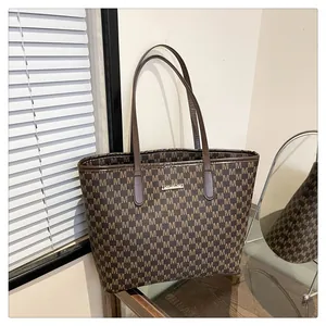 Detail of vintage monogram tote bag with brown M pattern and gold metal logo plaque