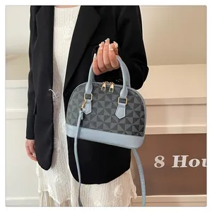 Nahaufnahme der Muscheltasche mit geometrischem Muster und goldfarbenen Metallbeschlägen