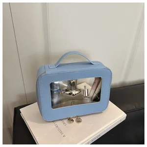 Sky blue makeup bag with Saffiano texture and clear window on a white book