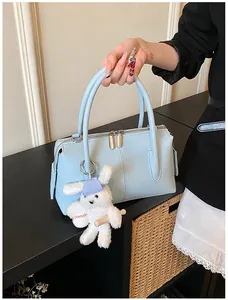 Close-up of light blue lychee pattern leather handbag with plush bunny charm accessory