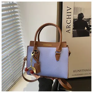 Détail du sac à main en cuir bicolore avec pendentif cerise et logo doré