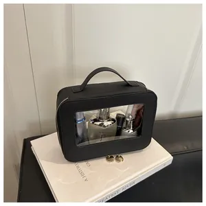 Detail of black leather makeup bag featuring a clear PVC window and gold double zippers