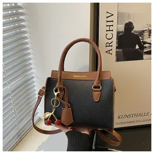 Détail d'un sac à main en cuir noir et marron avec breloque cerise et texte mode