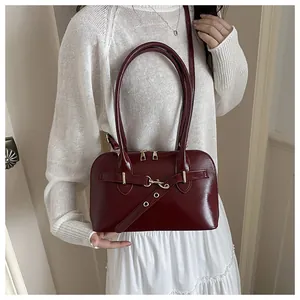Detailaufnahme der dunkelroten Leder-Bowlingtasche mit goldenen Beschlägen und Gurt