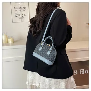 Detail einer geometrisch gemusterten Muscheltasche mit hellblauem Lederbesatz im Alltag