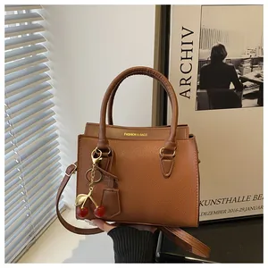 Détail du sac à main en cuir marron foncé texture litchi avec pendentif cerise chic