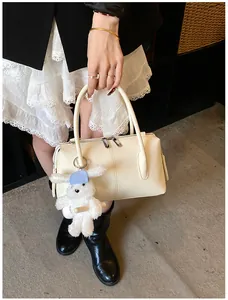 Detail of cream leather handbag with cute rabbit charm and textured finish on bag