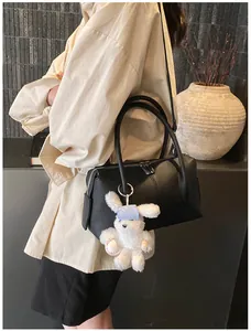 Close-up of black lychee texture leather boston bag with a cute white bunny pendant