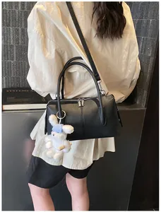 Close-up of black pebble leather Boston bag with plush bunny charm and silver hardware