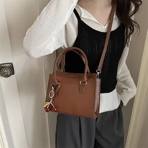 Sac bandoulière rétro en cuir marron foncé avec charm cerise et texte doré