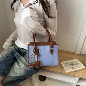 Sac à main minimaliste contrasté violet et marron avec pendentif cerise en situation