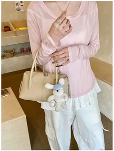 Chic beige grain leather boston bag with a cute teddy bear charm in a cafe setting