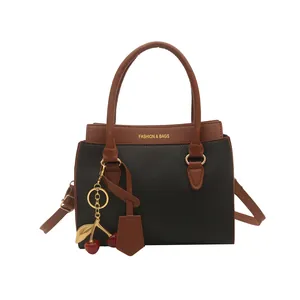 Sac à main minimaliste en cuir litchi noir avec poignées marron et charm cerise
