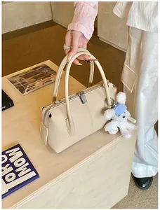 Detail of cream Boston bag featuring textured leather and a cute plush charm accessory