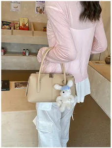 Close-up of beige lychee grain handbag with cute white rabbit plush doll charm