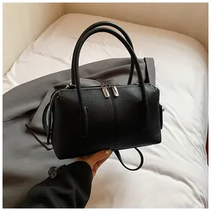 Close-up of black lychee grain leather handbag with dual metal zippers and round handles