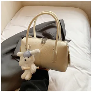Detailed view of cream pebble leather bag with silver zipper and white rabbit charm