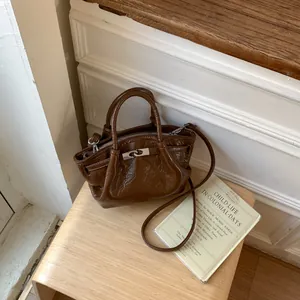 Dettaglio borsa a secchiello in pelle stropicciata marrone scuro con chiusura a scatto in metallo