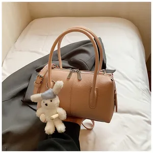 Detail view of apricot Boston bag with lychee texture and cute white rabbit plush charm