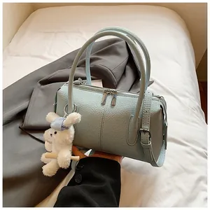 Close-up of light blue litchi grain leather bag with white plush bunny charm accessory