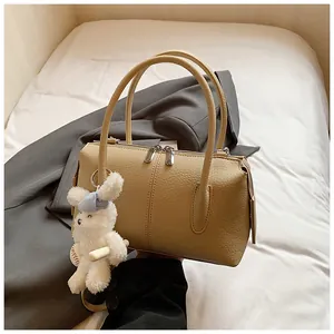 Detail of lychee pattern leather bag with silver zippers and a cute plush bunny charm
